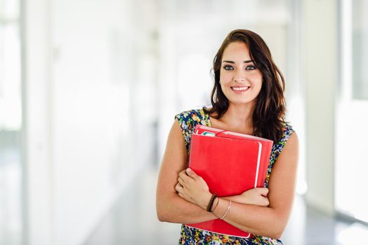 Young adult student woman in a hallway of her school smiling. Lifestyle and university education concepts.