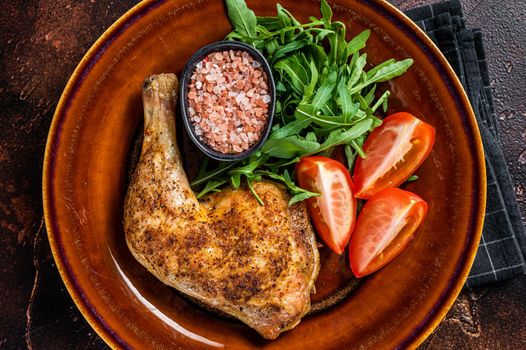 Poultry dish - roasted chicken legs with vegatables salad. Dark background. Top view.