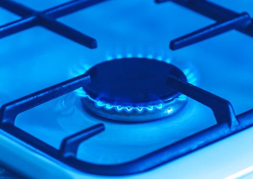 Gas burner with a blue flame on a gas stove, close-up.