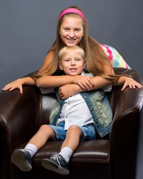 A teenage girl with her younger brother. studio photo session. The concept of family happiness.