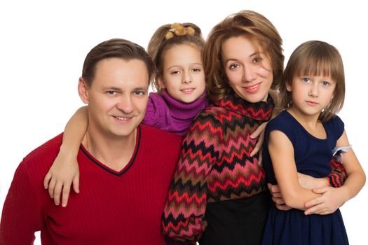 Portrait of a friendly young family of 4 people. Dad, mom and two cute daughters. The girls hug their parents . Close-up - Isolated on white background