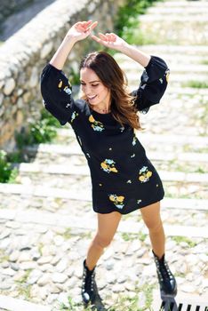 Middle-aged woman, model of fashion, wearing flowered dress in an old neighborhood of Granada in summer