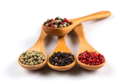 Wooden spoons with various pepper spice on white background