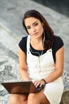 Beautiful young woman using laptop computer sitting on urban steps. Businesswoman wearing casual clothes working outdoors. Lifestyle concept.