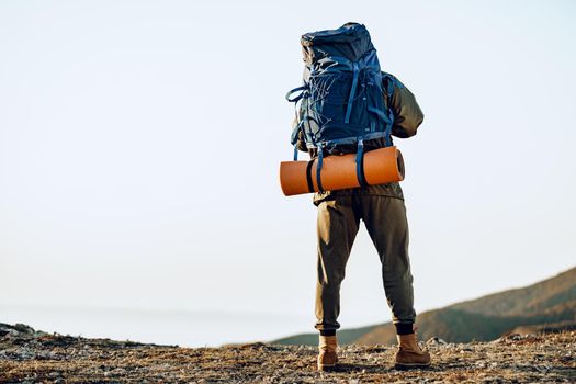 Unrecognizable man hiker got to the top of the mountain and looks down onto the valley