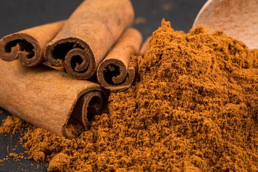 cinnamon sticks with powder on dark stone plate