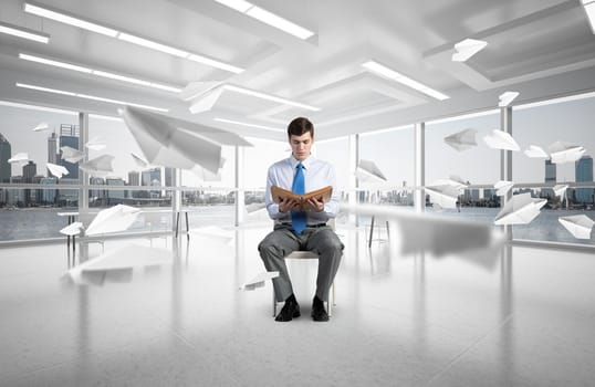 young businessman with book on office chair