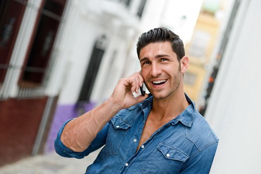 Portrait of good looking man in urban background talking on phone