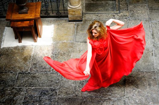 Portrait of a beautiful blonde woman, wearing a red dress, jumping