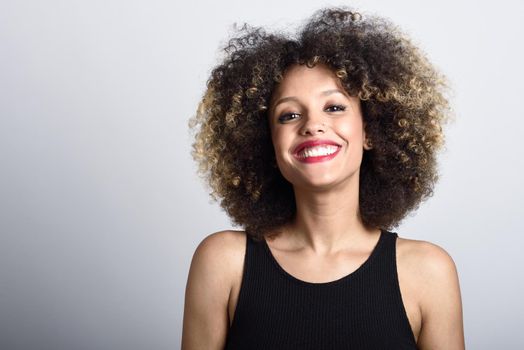 Young black woman with afro hairstyle smiling. Girl wearing black dress. Studio shot.