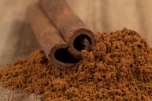 Cinnamon sticks with cinnamon powder on wooden background