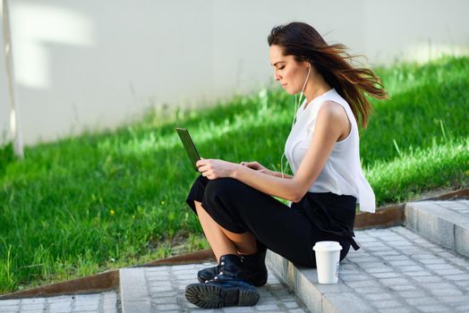 Young businesswoman working with her laptop computer sitting on urban steps outdoors.