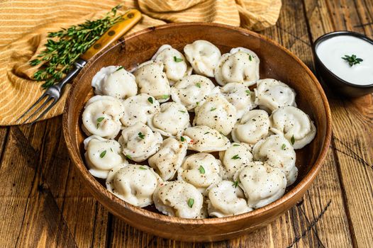 Homemade Russian Dumplings Pelmeni with beef and pork meat in a wooden bowl. wooden background. top view.