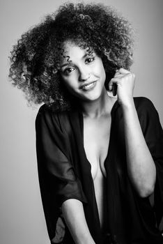 Young black woman with afro hairstyle laughing. Girl wearing black clothes. Studio shot. Black and white photograph