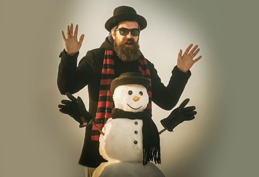 Winter man with happy face and snowman in black hat. Snowman, winter holiday celebration
