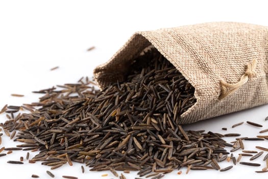 Close up image of a heap of wild rice on white background in a hessian sack