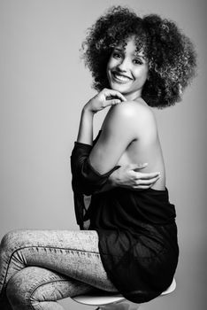 Young black woman with afro hairstyle laughing. Girl wearing black clothes. Studio shot. Black and white photograph