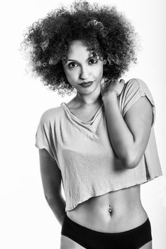 Young black woman with afro hairstyle. Girl wearing t-shirt and black panties. Studio shot.