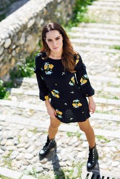 Middle-aged woman, model of fashion, wearing flowered dress in an old neighborhood of Granada in summer