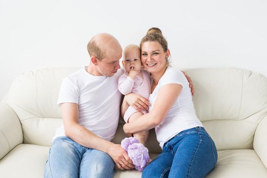 Proud mother and father smiling at their newborn baby daughter at home.