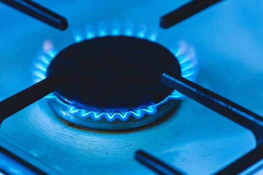 Gas burner with a blue flame on a gas stove, close-up.