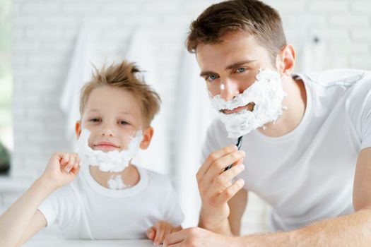 Father and his little son shaving together in bathroom