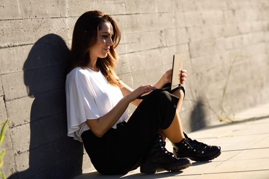 Young businesswoman working with her laptop computer sitting on the floor outdoors.