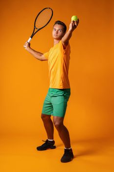 Full-length portrait of a tennis player man in action against orange background close up