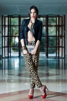Portrait of young beautiful woman, model of fashion, wearing leopard pants, jacket and red high heels