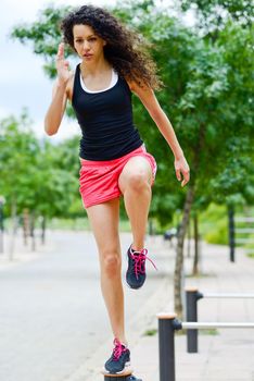 Portrait of young cheerful smiling woman in sports wear in urban background