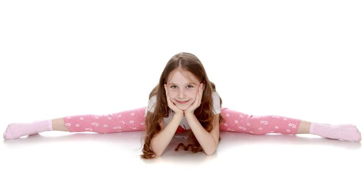 Beautiful little girl with long brown hair to her waist . Girl the girl is very flexible , she does the splits on the floor - Isolated on white background