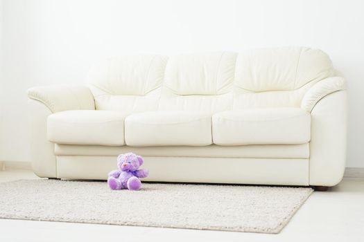 Childhood and babyhood concept - Teddy bear seated on beige carpet at bedroom.