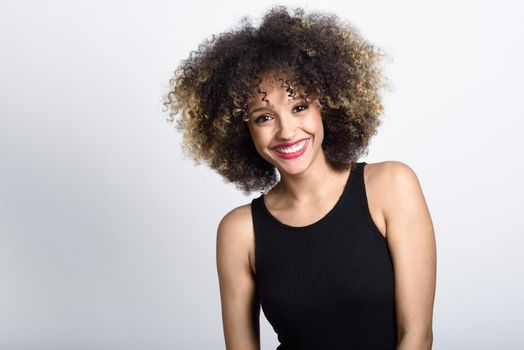 Young black woman with afro hairstyle smiling. Girl wearing black dress. Studio shot.