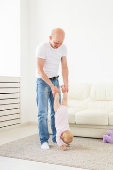 Fatherhood and family concept - Father and small toddler baby indoors at home, playing