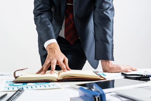 Businessman analyzing financial documents at office desk. Financial expertise and consulting. Manager in suit and tie planning day with personal organizer. Time management and work organization.