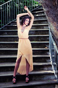 Portrait of a beautiful young woman, model of fashion, in a garden stairs.
