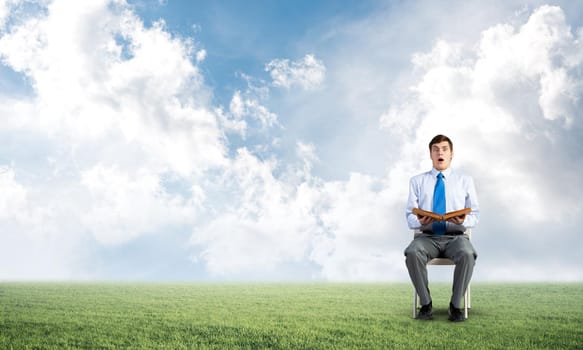 young businessman with book on office chair