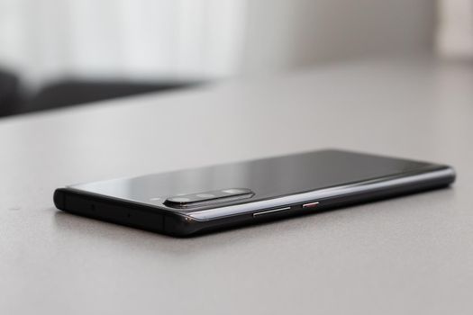 Black modern mobile phone with blank screen on black stone table background. Smartphone on old dark grey vintage texture background.