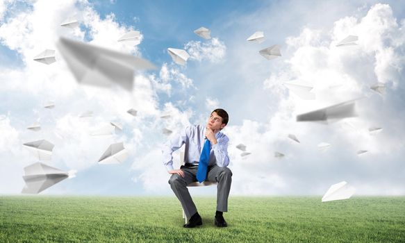 young businessman sits on an office chair, thoughtful and looking up