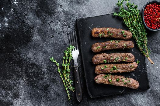 Grilled Shish kebab meat sausages. Black background. Top view. Copy space.