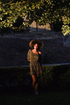 Young black woman with afro hairstyle standing in urban background. Mixed girl wearing casual clothes.