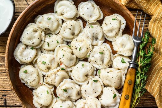 Homemade Russian Dumplings Pelmeni with beef and pork meat in a wooden bowl. wooden background. top view.