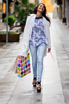 Portrait of a beautiful woman with shopping bags walking along a commercial street