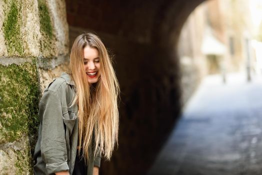 Portrait of happy blonde girl smiling in urban background