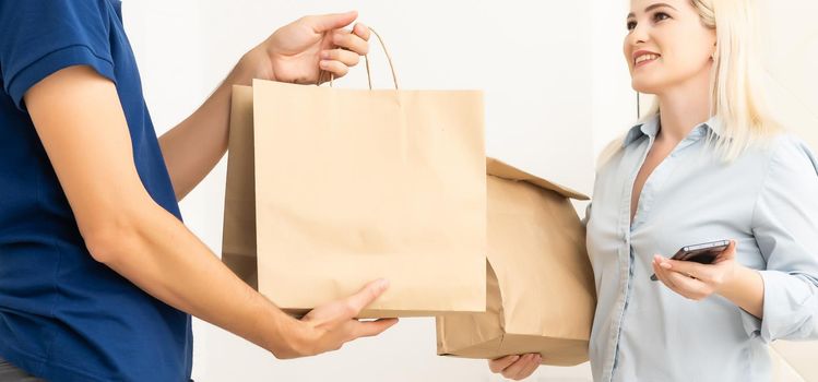 Woman and courier during order transfer. Woman accepting delivery from deliveryman. Cropped image of delivery service worker giving parcel to client.