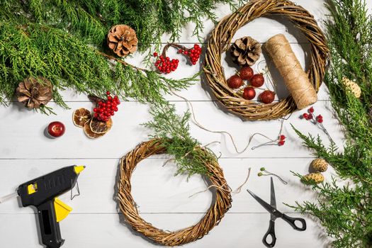 Make a Christmas wreath with your own hands. Spruce branch, Christmas wreath and gifts on a white wooden background. Workplace for preparing handmade decorations. Christmas and New year