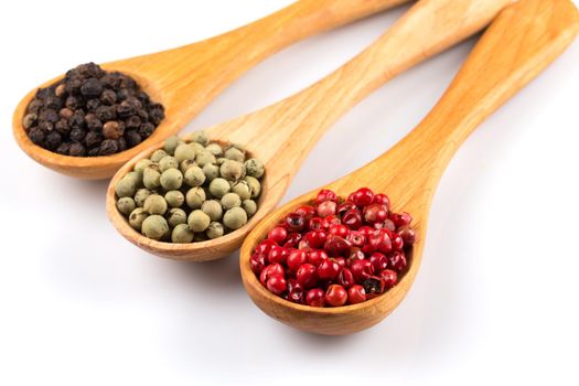 Wooden spoons with various pepper spice on white background