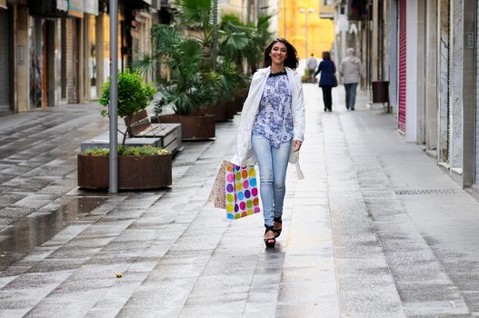 Portrait of a beautiful woman with shopping bags walking along a commercial street