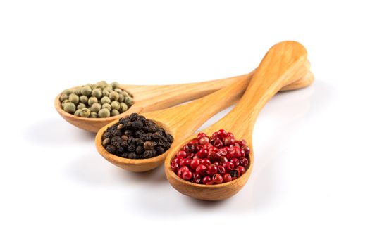 Wooden spoons with various pepper spice on white background