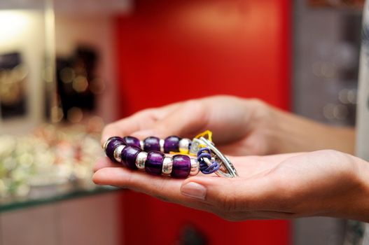 Close-up of hands of woman taking a bracelet in a jewelry store